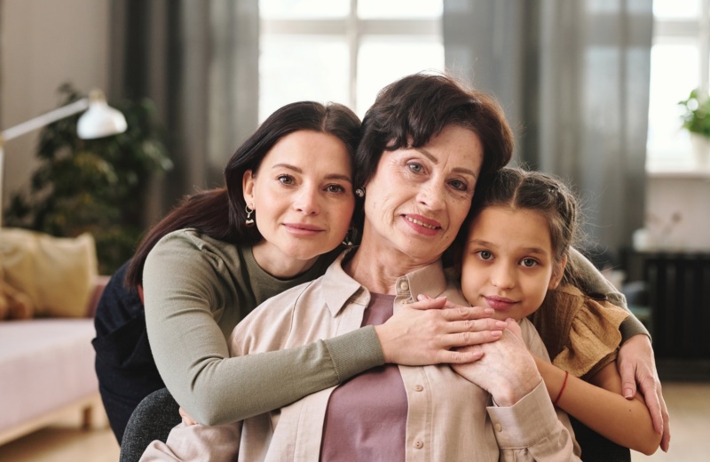 Young mother and her cute little daughter embracing mature brunette female