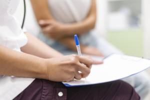 Image d'un professionnel de santé prenant des notes lors d'une consultation avec sa patiente 