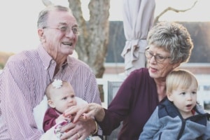 Photo d'une famille : 
Un grand père, à gauche, tenant dans ses bras son petit-enfant
Une grand mère, à droite, tenant dans ses bras son petit-enfant
